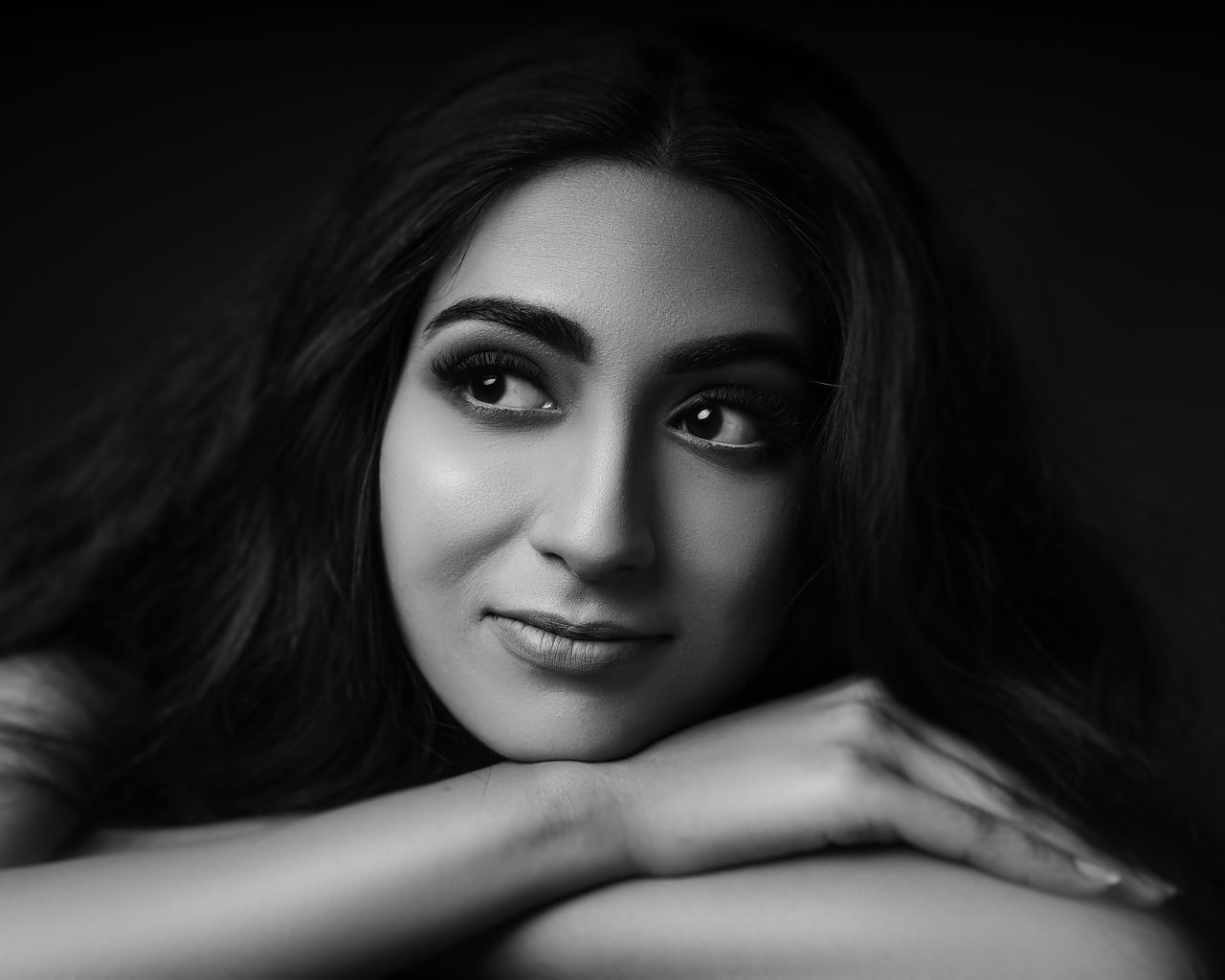 A captivating monochrome portrait of a woman with a thoughtful expression and arms crossed.